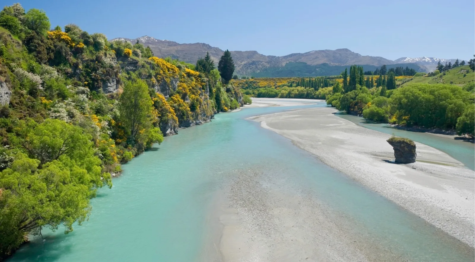 A wide river bend with pale gravel bars and autumn trees along the bank