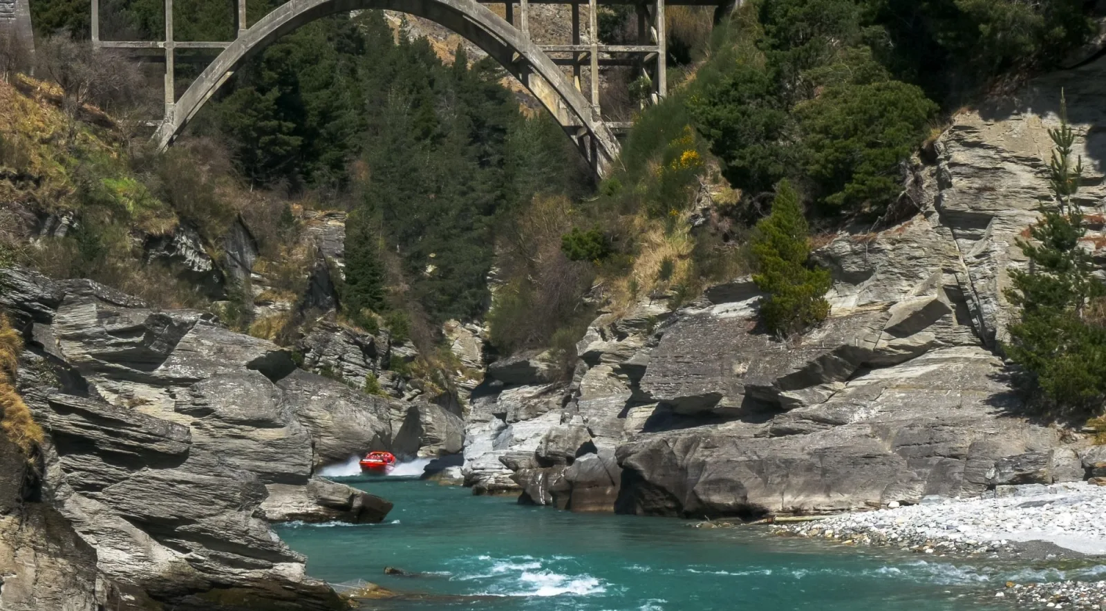 A small boat dwarfed by the canyon walls on a turquoise stretch of river