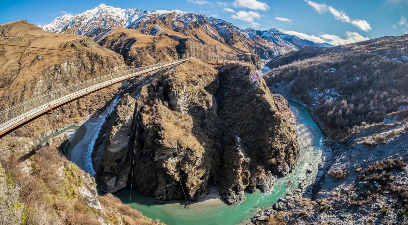 Aerial view of a narrow bridge crossing a deep, tightly curving river gorge